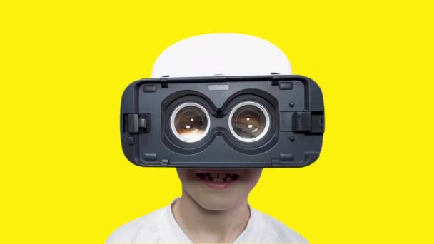 巨大な目で仮想現実のメガネで陽気な男の子 バーチャルビデオを見て笑っている子供 サイバーパンク 球状ビデオ 拡張現実 少年はコンピュータゲームをする 将来の技術 — ストック動画