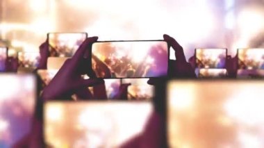 Konser sırasında havada yüzen altın konfetileri. Kalabalık bir konser izliyor, şarkı söylüyor, zıplıyor. Hayranlar akıllı telefonlardan video kaydediyor. Bir sürü akıllı telefon. Canlı yayın. Hikayeler. Sahne ışığı.