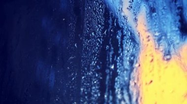 Bardaktan aşağı yağmur damlaları akıyor. Güneş ıslak pencereden içeri giriyor. Sisli pencere, yakın plan. Pencere eriyor. Yağmurlu bir pencerede sabah güneşi. Bahar ısınması.