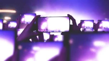 Konser sırasında havada yüzen altın konfetileri. Kalabalık bir konser izliyor, şarkı söylüyor, zıplıyor. Hayranlar akıllı telefonlardan video kaydediyor. Bir sürü akıllı telefon. Canlı yayın. Hikayeler. Sahne ışığı.