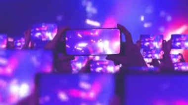 Konser sırasında havada yüzen altın konfetileri. Kalabalık bir konser izliyor, şarkı söylüyor, zıplıyor. Hayranlar akıllı telefonlardan video kaydediyor. Bir sürü akıllı telefon. Canlı yayın. Hikayeler. Sahne ışığı.