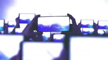 Kalabalık bir konser izliyor, şarkı söylüyor, zıplıyor. Konser sırasında havada yüzen altın konfetileri. Hayranlar akıllı telefonlardan video kaydediyor. Bir sürü akıllı telefon. Canlı yayın. Hikayeler. Sahne ışığı.