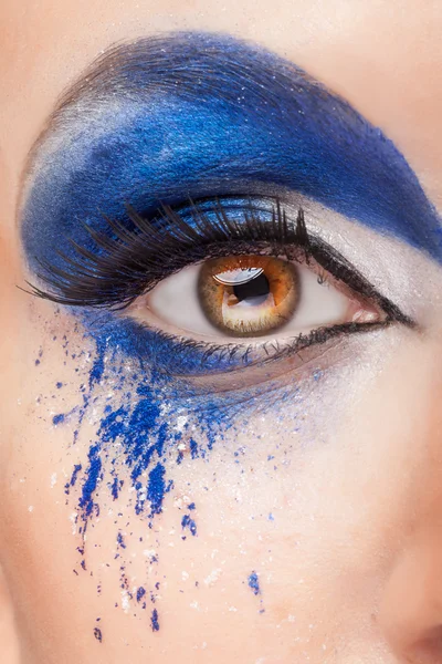 Close up image of an eye with blue fantasy make up