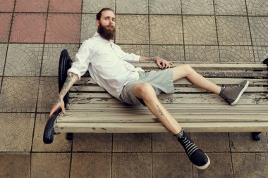 Serin görünümlü adam tatoos ile ve sandalye pos üzerinde oturan uzun sakal