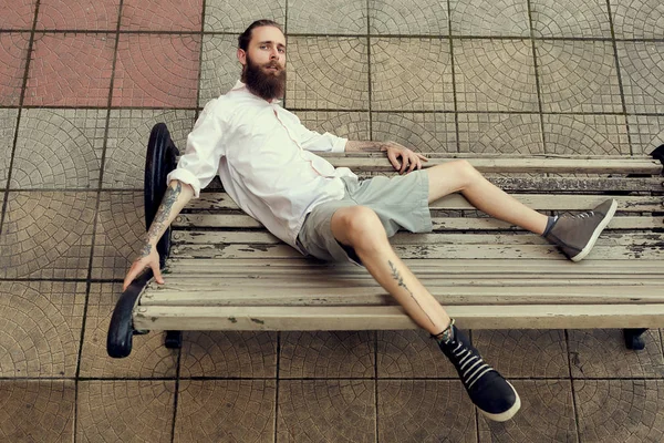 Serin görünümlü adam tatoos ile ve sandalye pos üzerinde oturan uzun sakal