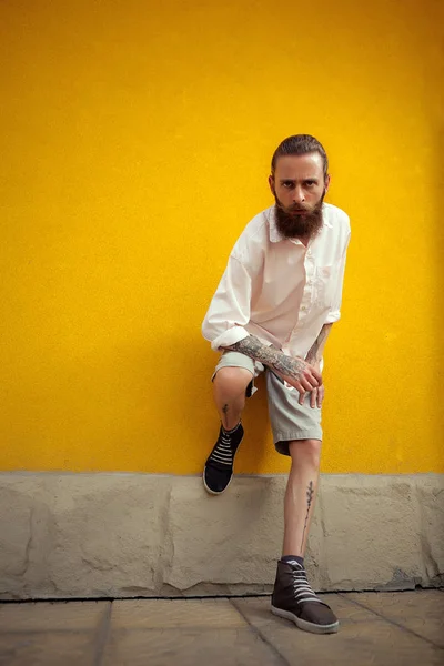 Hipster posing on yellow wall — Stock Photo, Image