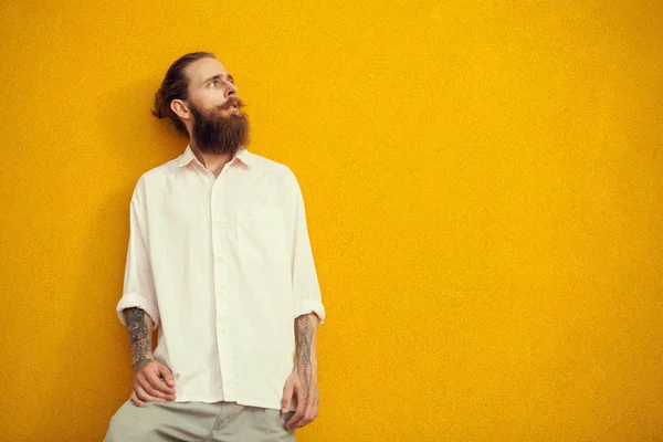 Bearded and tattooed man posing on yellow wall — Stock Photo, Image