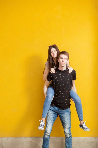 Couple heureux posant sur un mur jaune — Photo