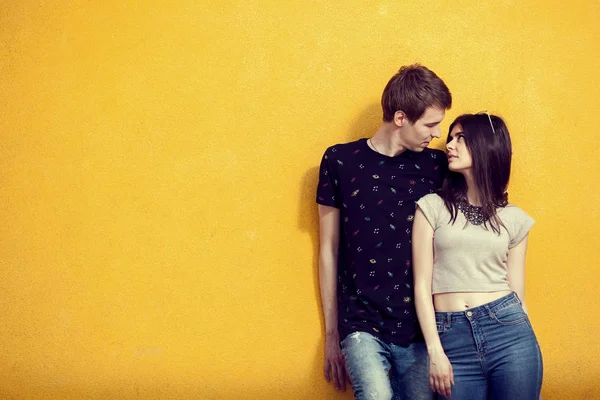 Casal posando em estilo de moda na parede amarela — Fotografia de Stock