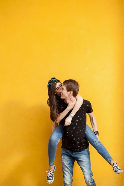 Happy laughing couple on yellow wall — Stock Photo, Image