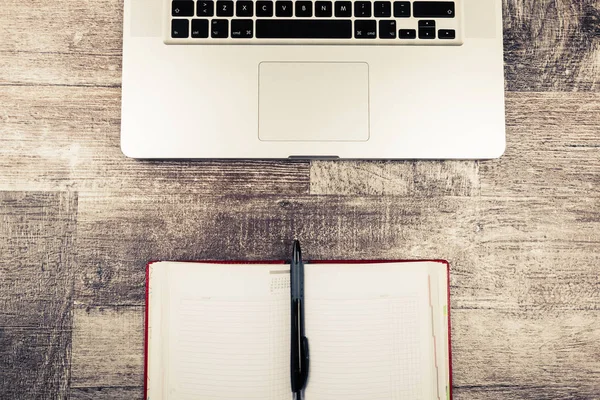 Open writing notebook next to a laptop