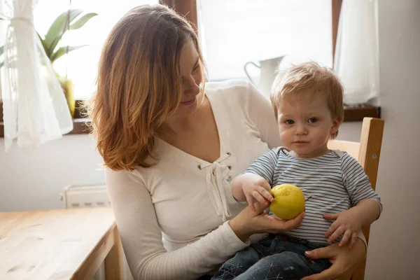 Маленька дитина намагається з'їсти яблуко на кухні — стокове фото