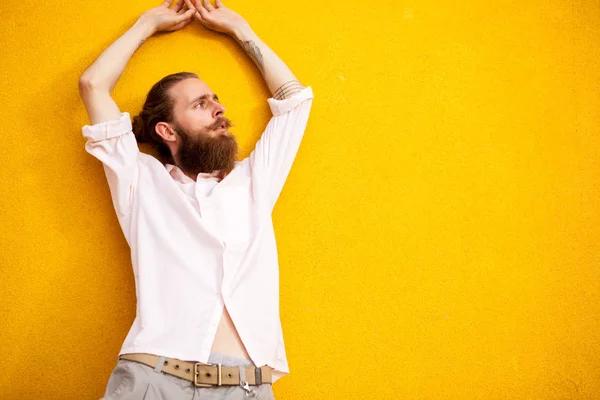 Homme barbu tatoué sur un mur jaune — Photo