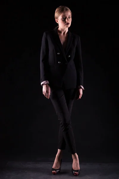 Beautiful fashionable woman in suit on black background
