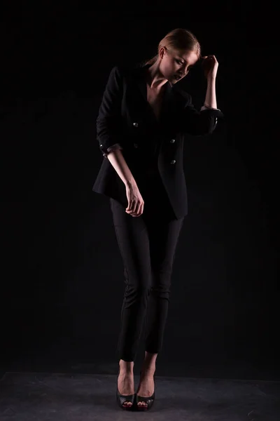 Fashionable woman in suit on black background