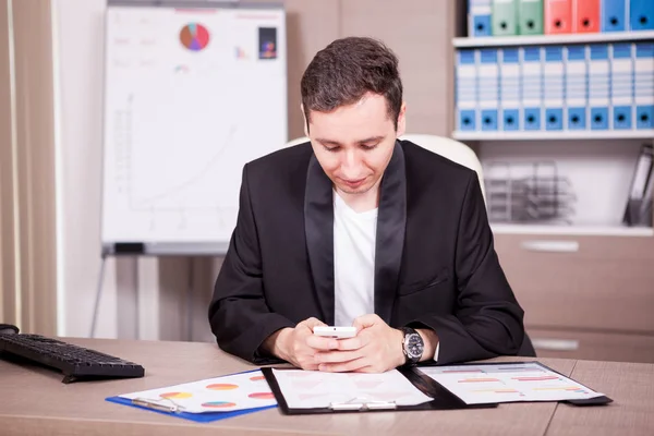 Businessman with phone in hands and charts on table