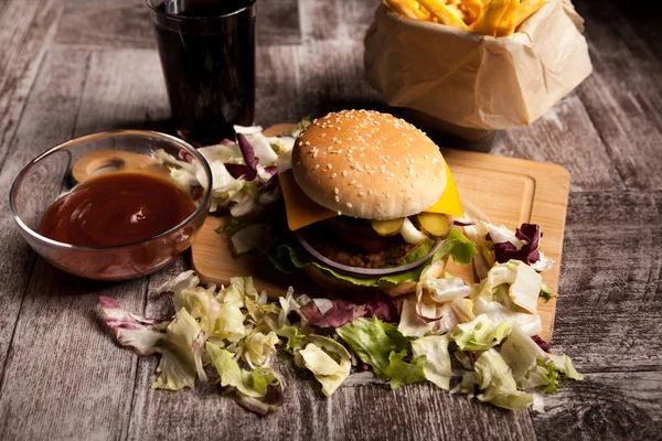 Вкусные домашние гамбургеры на деревянной тарелке рядом с фритюром и соусом — стоковое фото