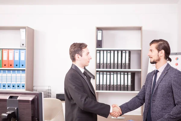 Jovens parceiros de negócios apertando as mãos no escritório — Fotografia de Stock