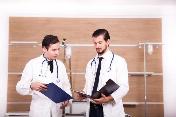 İki doktor hastane kurtarma odasında elinde klasörlerle konuşmak — Stok fotoğraf