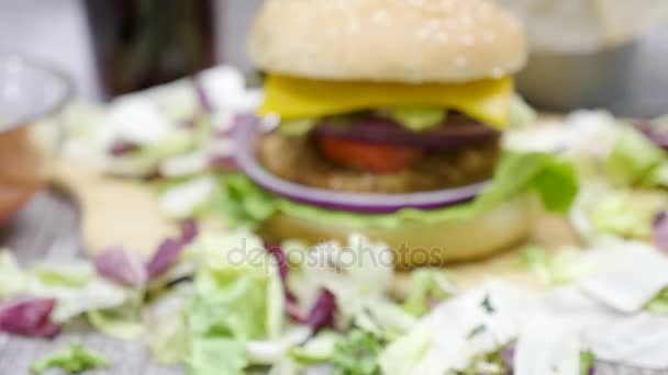 Vergrößern aus dem Fokus auf Hamburger mit Pommes auf Holztisch — Stockvideo