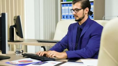 Bilgisayarda çalışarak ve telefonda konuşurken işadamı