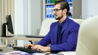 Tipik üstünde bilgisayar ve telefonda konuşurken işadamı