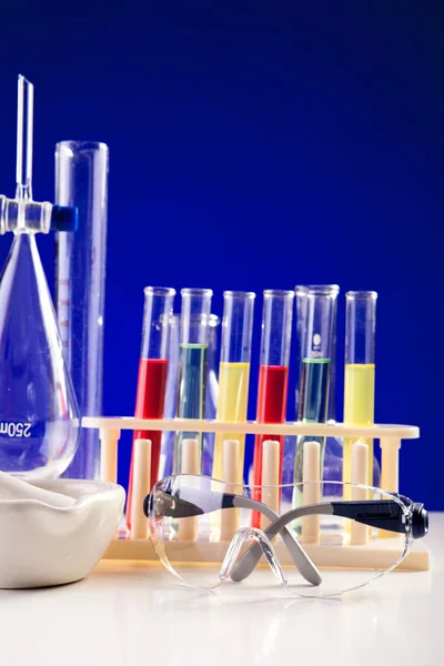 Laboratorio de química sobre una mesa con anteojos protectores sobre blu — Foto de Stock
