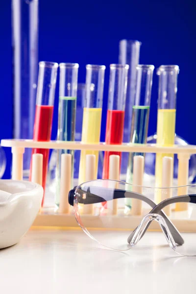 Chemie-Laborgeräte auf einem Tisch vor blauem Hintergrund — Stockfoto