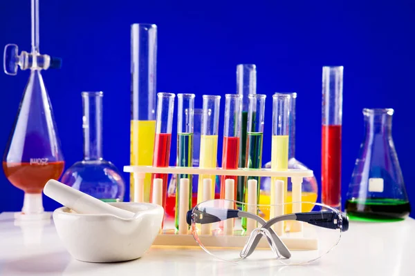 Chemie-Laborgeräte auf einem Tisch vor blauem Hintergrund — Stockfoto