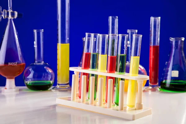 Chemie-Laborgeräte auf einem Tisch vor blauem Hintergrund — Stockfoto