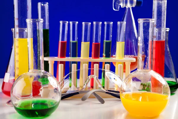 Laboratório de química diferente em uma mesa sobre fundo azul — Fotografia de Stock