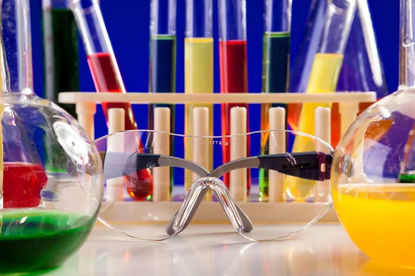 Equipamento de química colocado em uma mesa sobre fundo azul — Fotografia de Stock