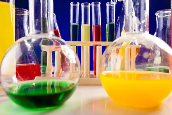 Equipamento de química colocado em uma mesa sobre fundo azul — Fotografia de Stock