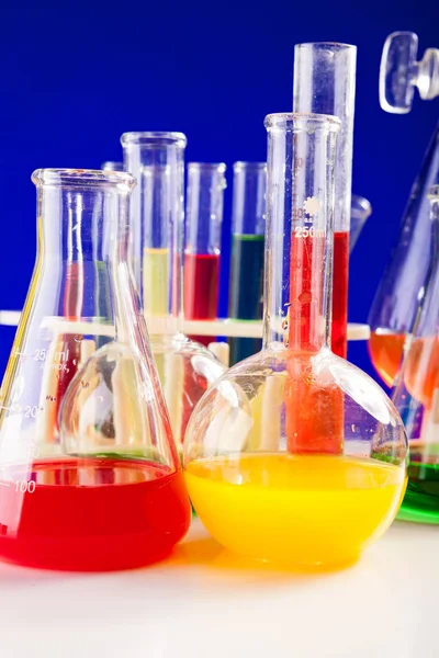 Laboratório de química com líquidos coloridos em uma mesa sobre costas azuis — Fotografia de Stock
