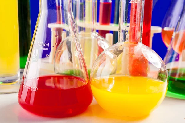 Liquido colorato in chimica impostato su un tavolo su sfondo blu — Foto Stock