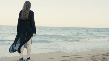 Kadın siyah uzun sallayarak Fularlı beack üzerinde yürüme