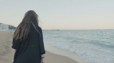 Kadın siyah uzun sallayarak Fularlı beack üzerinde yürüme