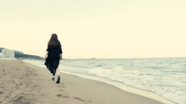 Kadın siyah uzun sallayarak Fularlı beack üzerinde yürüme