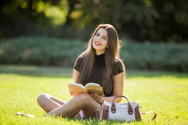 Beautiful young woman enjoying reading outside in the park