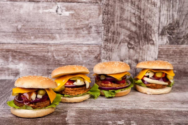 Deliziosi gustosi hamburger su sfondo di legno — Foto Stock