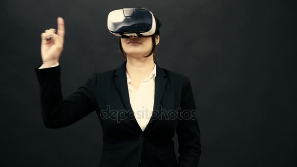 Жінка в костюмі в гарнітурі VR на чорному студійному фоні відчуває віртуальну реальність — стокове відео