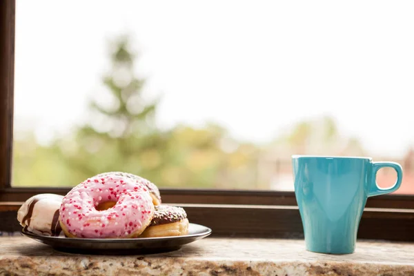 Donuts y una taza de café al lado del alféizar de la ventana — Foto de Stock