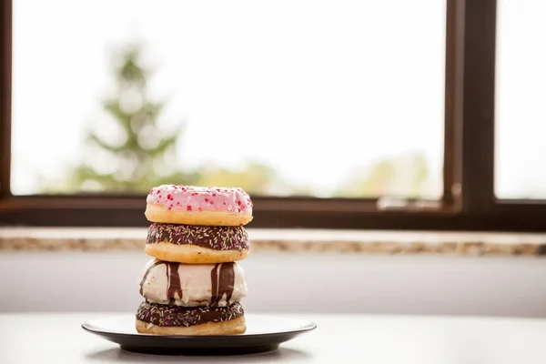 Plaat met donuts naast venster — Stockfoto