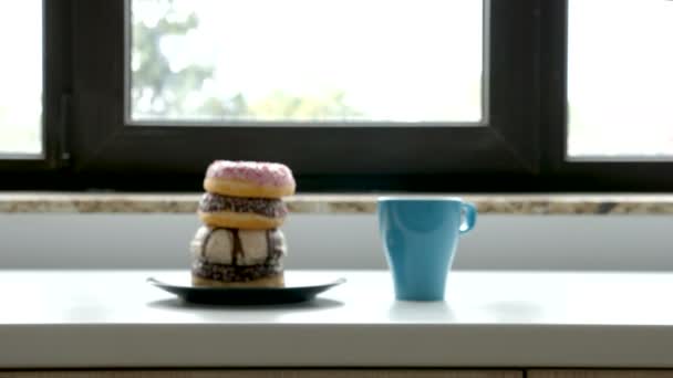 Kopje koffie en donuts op plaat naast een venster — Stockvideo