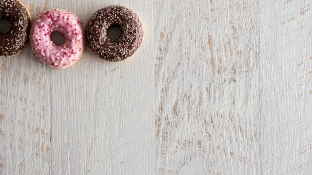 Stop motion of donuts on white wooden background — Stock Video