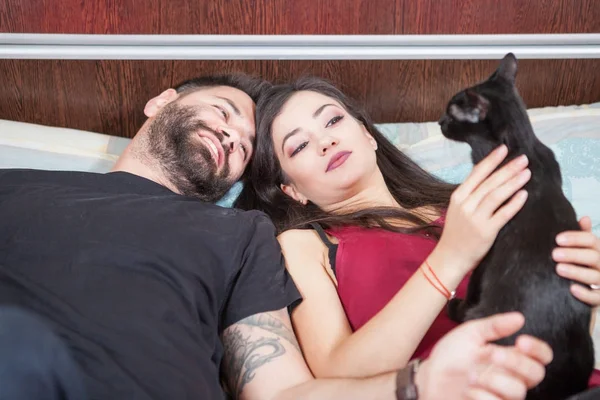 Young inlove couple on the bed with their cats