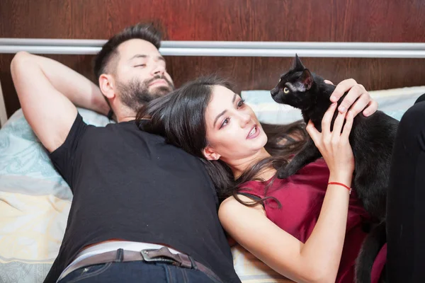 年轻的相爱夫妇和他们的猫到床上 — 图库照片