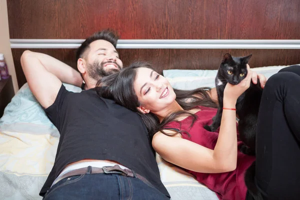Jeune couple amoureux sur le lit avec leurs chats — Photo