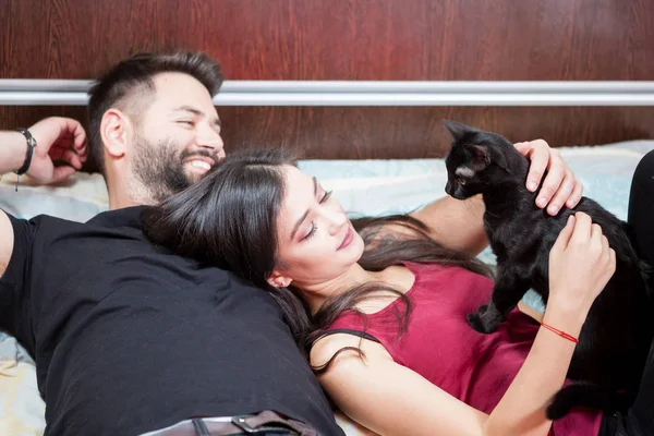 Jeune couple amoureux sur le lit avec leurs chats — Photo