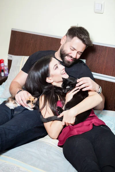 年轻的相爱夫妇和他们的猫到床上 — 图库照片